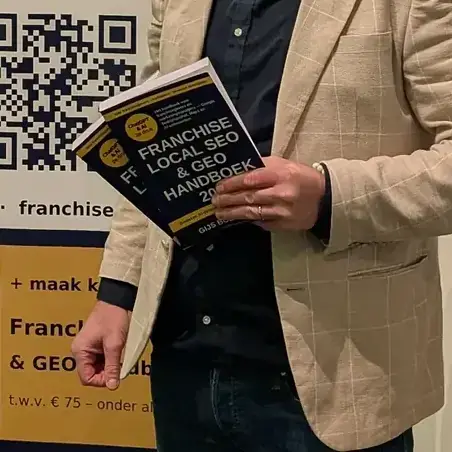 Gijs Bodenstaff houdt het Franchise Local SEO & GEO Handboek 2027 vast voor een rolbanner op de franchisebeurs in Gorinchem